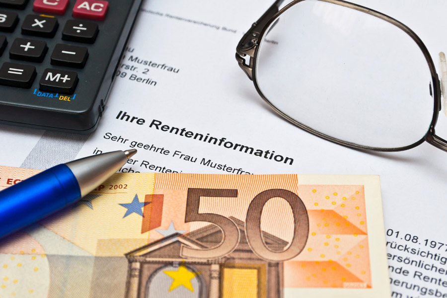Ein Stift, eine Brille, ein Taschenrechner und eine Renteninformation liegen auf einem Tisch neben einem 50-Euro-Schein.